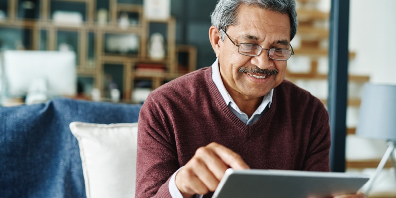 man smiling and using tablet for mobile banking