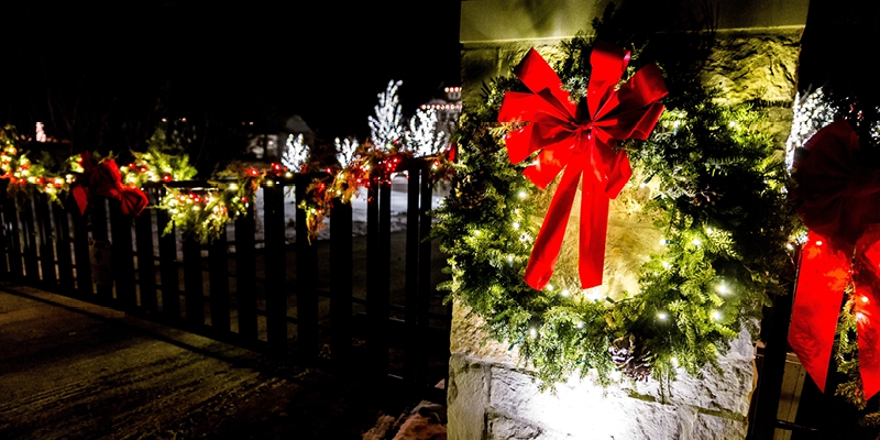 wreath and ribbon on a column lit up by spotlight and string lights