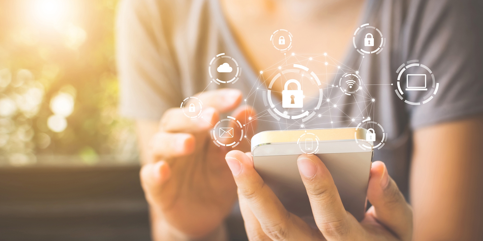close up of cell phone being held with icons of locks, envelopes, laptops, and clouds above the phone
